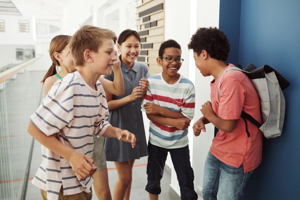 A happy group of diverse teenagers laughing and chatting in an indoor setting.